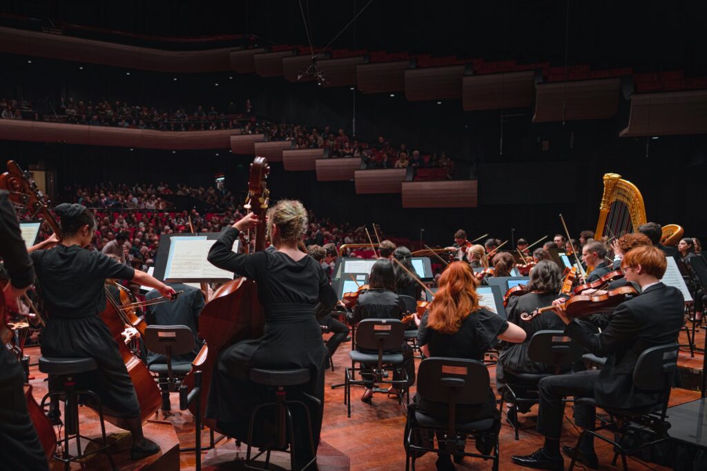 An orchestra of young musicians perform on stage.