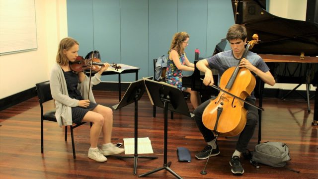 AYO Chamber Players - A piano trio rehearses in a classroom.