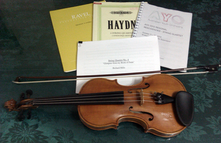 Sheet music arranged next to a violin and bow.