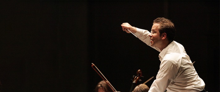 Anthony Hermus conducting with black background