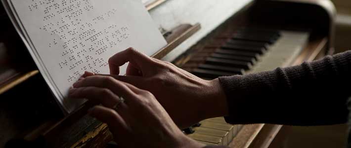 A musician reads braille sheet music with his fingertips.