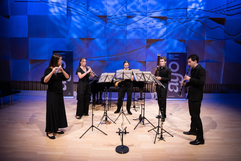 A wind quintet rehearses in a small chamber venue.