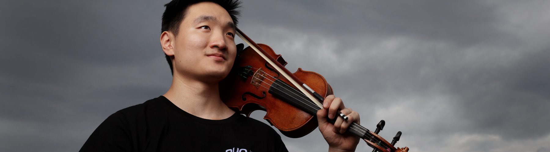 Young musician with his violin in the shoulder with a cloudy background