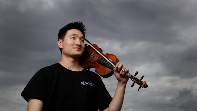 Young musician with his violin in the shoulder with a cloudy background