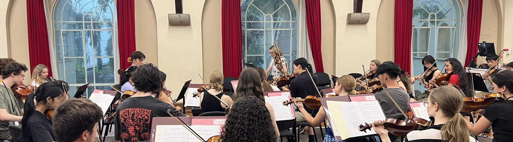 A chamber orchestra rehearses in a room.