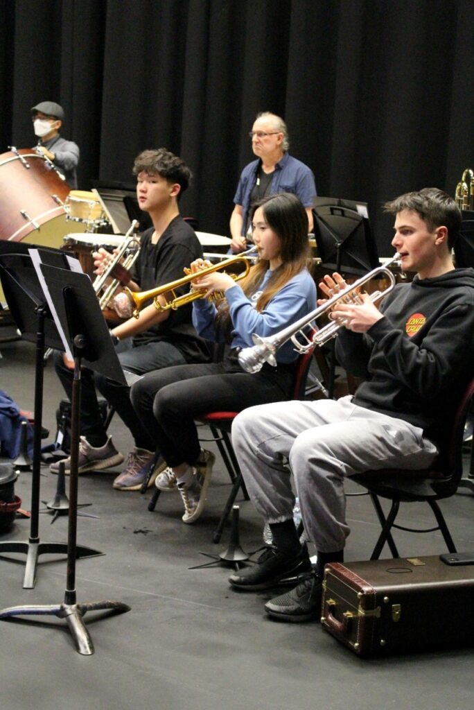 Three trumpet players seated during an orchestral rehearsal.
