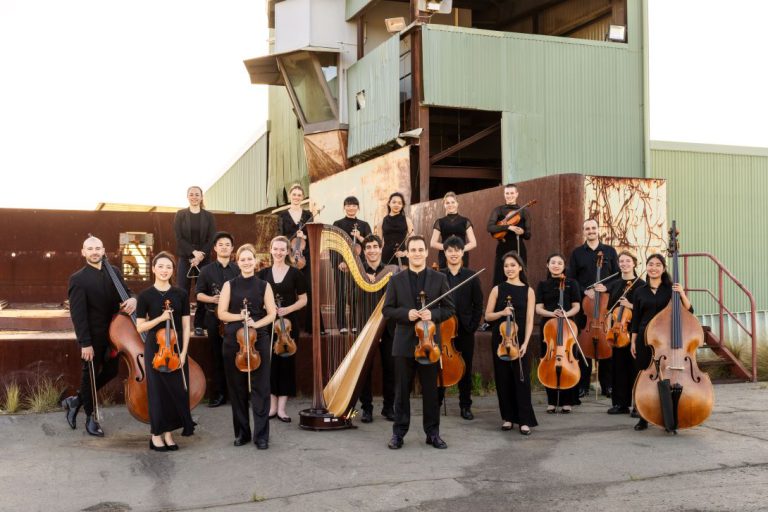 Group of musicians smiling and looking at the camera on a industrial site as background