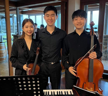 Merryvale Trio - Three young people stand in a line and smile at the camera. They are wearing concert black attire.