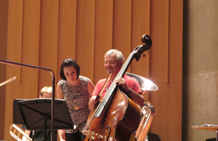 A double bassist and a composer stand on stage while workshopping a piece of music.
