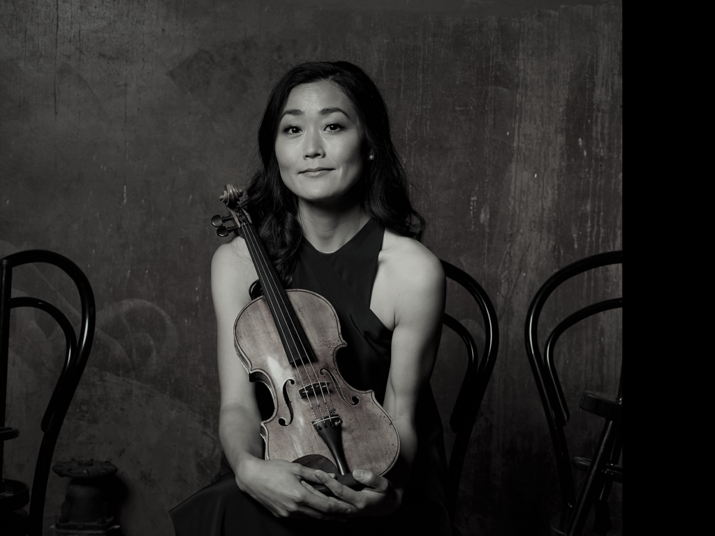 Greyscale portrait of ASO concertmaster Natsuko Yoshimoto holding her violin. 