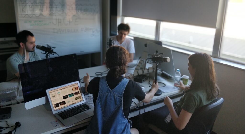 Four people sit in a room recording a podcast episode during AYO National Music Camp 2019. 