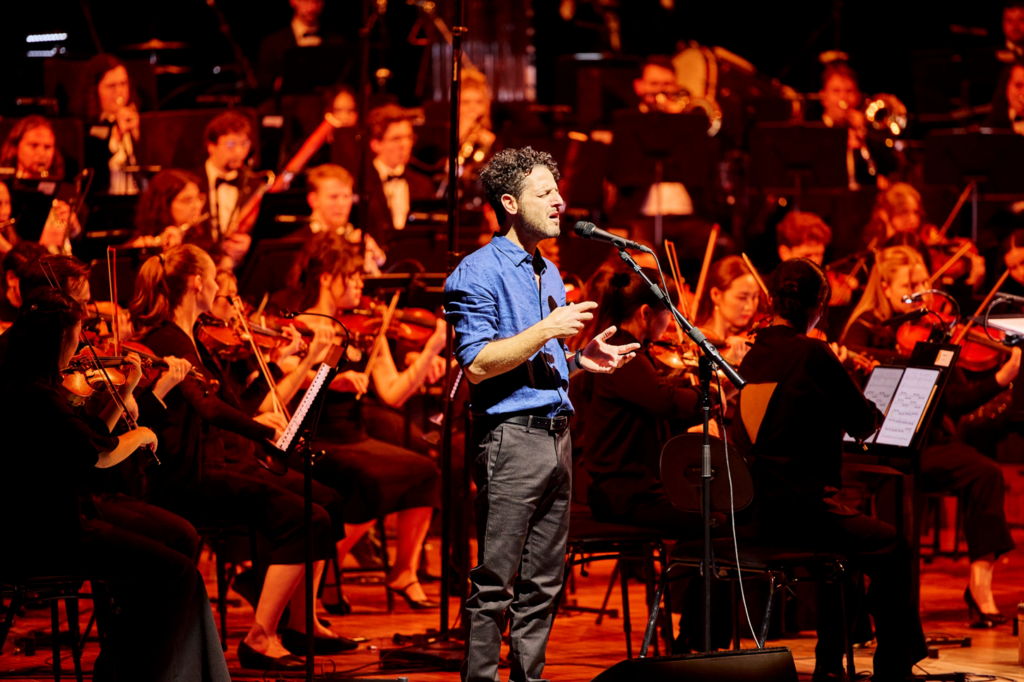 Singer-songwriter Lior performs on stage with the Australian Youth Orchestra.