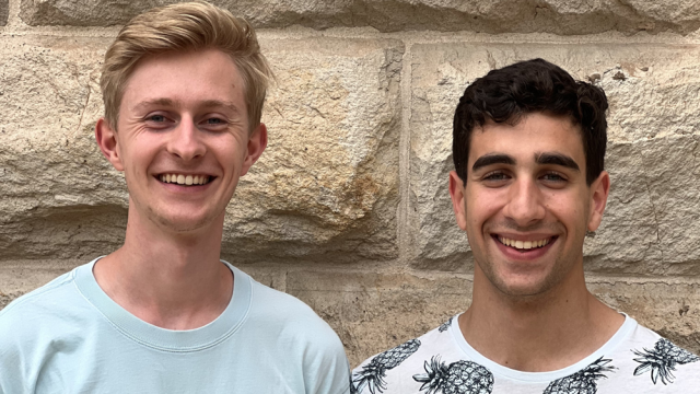 Two young men smile at the camera.