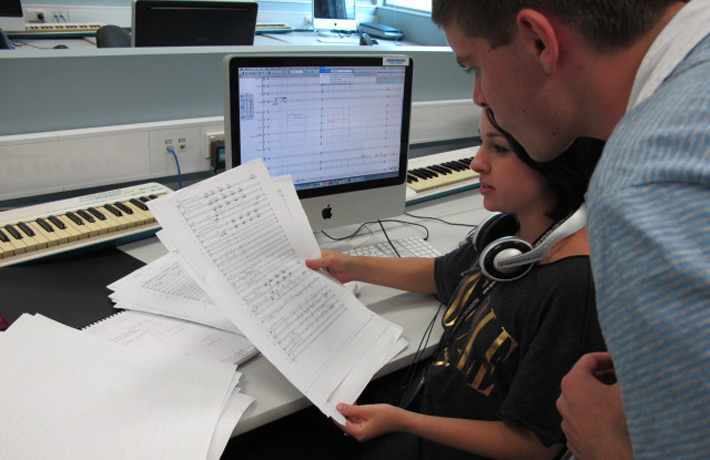 Two young composers look over sheet music