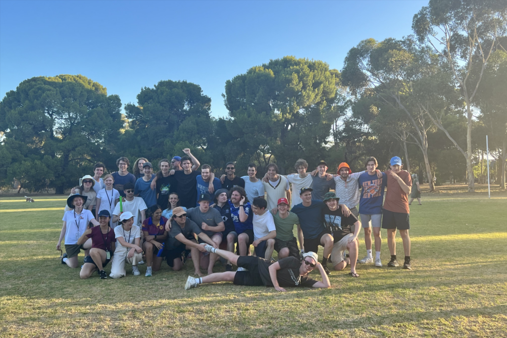 A group of young musicians smile at the camera while standing together on a cricket oval